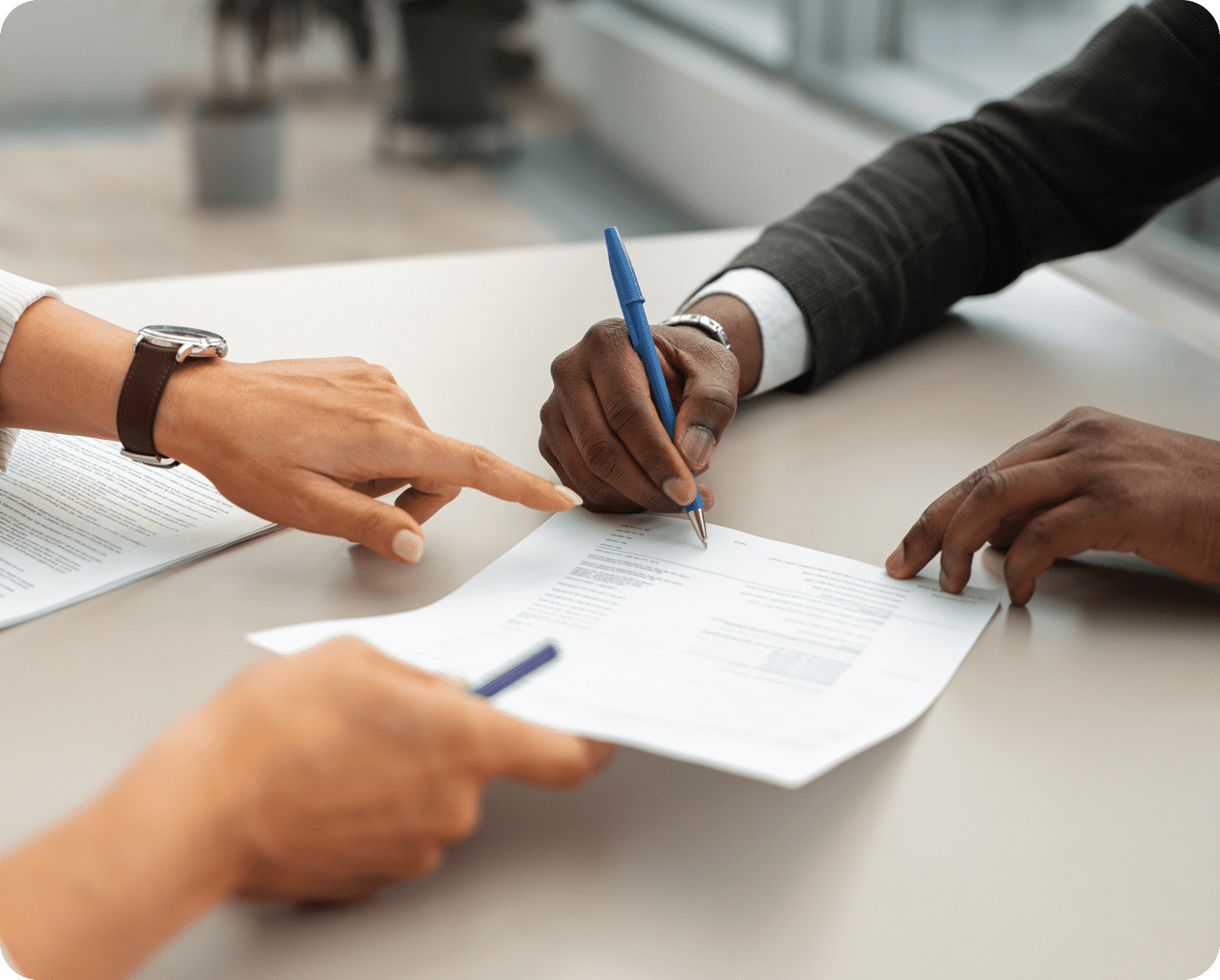 Hands signing and pointing at a document.